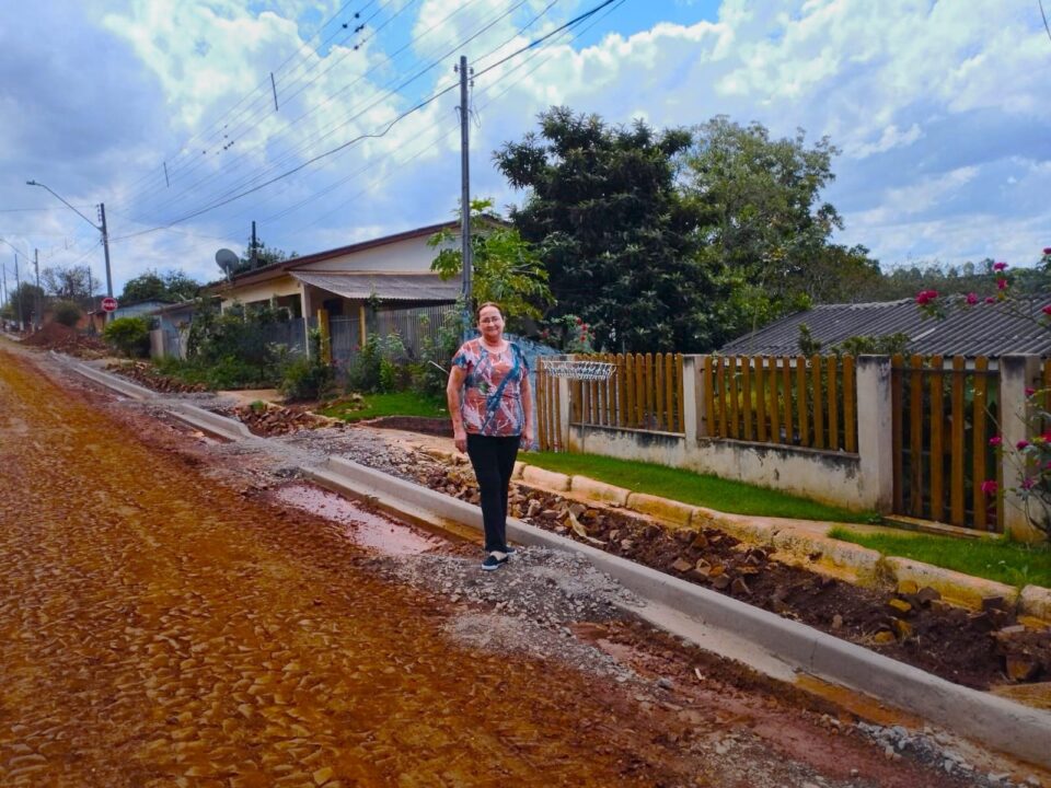 Fotografia mostra a copeira Maria Helena da Silva comemorando a pavimentação em sua rua, na cidade de Nova Tebas.