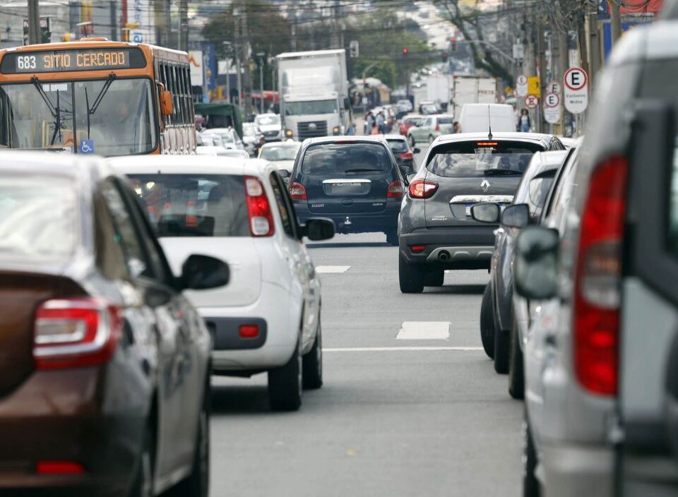 Fotografia mostra trânsito em rua de Curitiba, com vários carros. Projeto muda cobrança do IPVA.